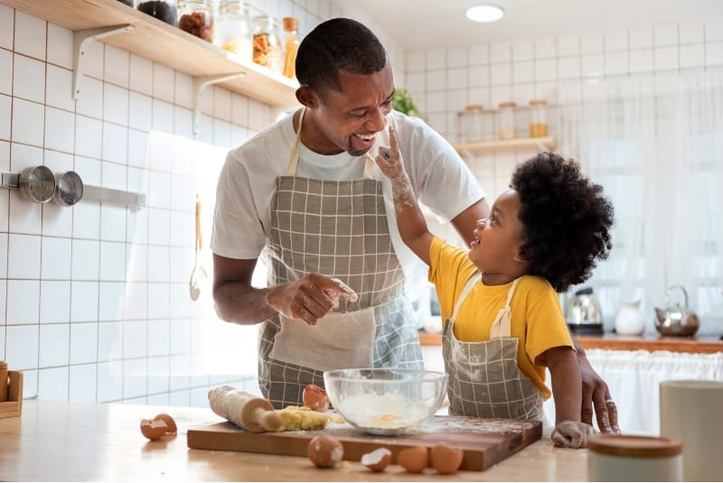 father and child baking together and smiling